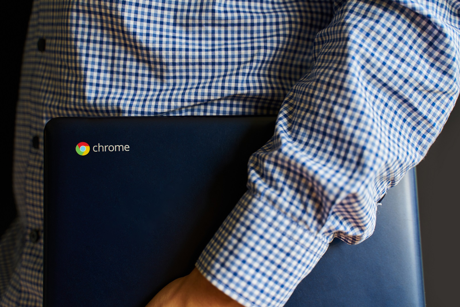 Man in checked shirt holding a chromebook