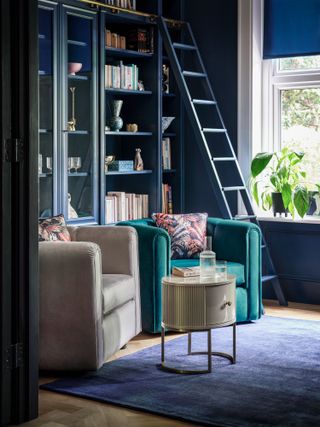 small den with armchairs and bookshelves with ladders