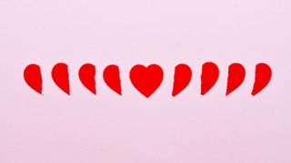 paper red hearts broken with full heart in middle on pink background