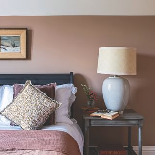 Bedroom painted in light brown with oversized lamp on wooden bedside table