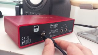 A man plugs a USB cable into an audio interface