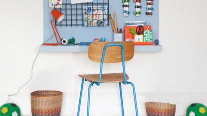 A kids&#039; desk made from an IKEA shelf with a chair, storage baskets and a desk lamp