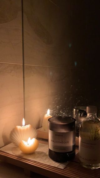 Byredo candle burning on bathroom shelf