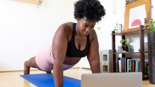 Woman doing a push up while looking at laptop screen.