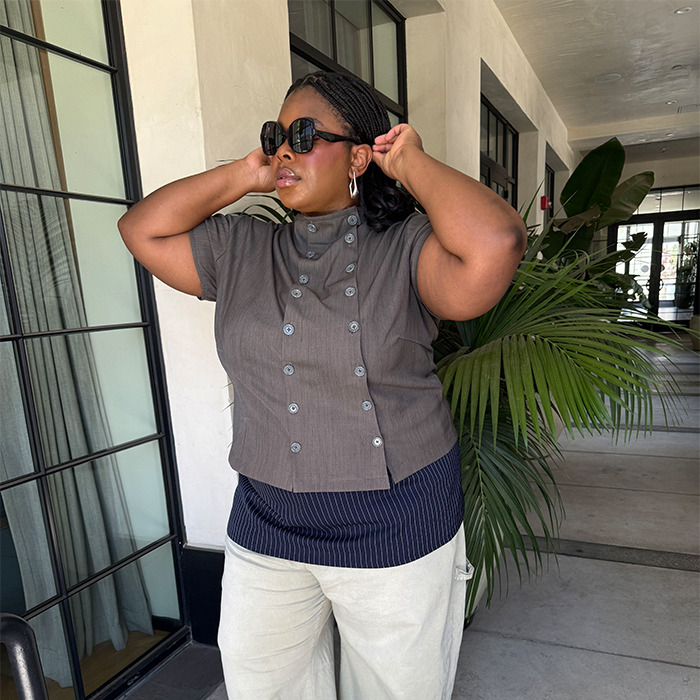 Chichi wears gray double breasted button up short sleeve shirt, green khaki barrel-leg pants, a pinstripe mini skirt, and black patent split toe tabi shoes.