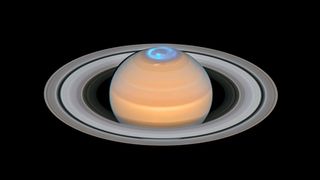 dusty orange color Saturn has a distinct flowing blue potion over the north pole, this is the planet's aurora as imaged by the Hubble Space Telescope.