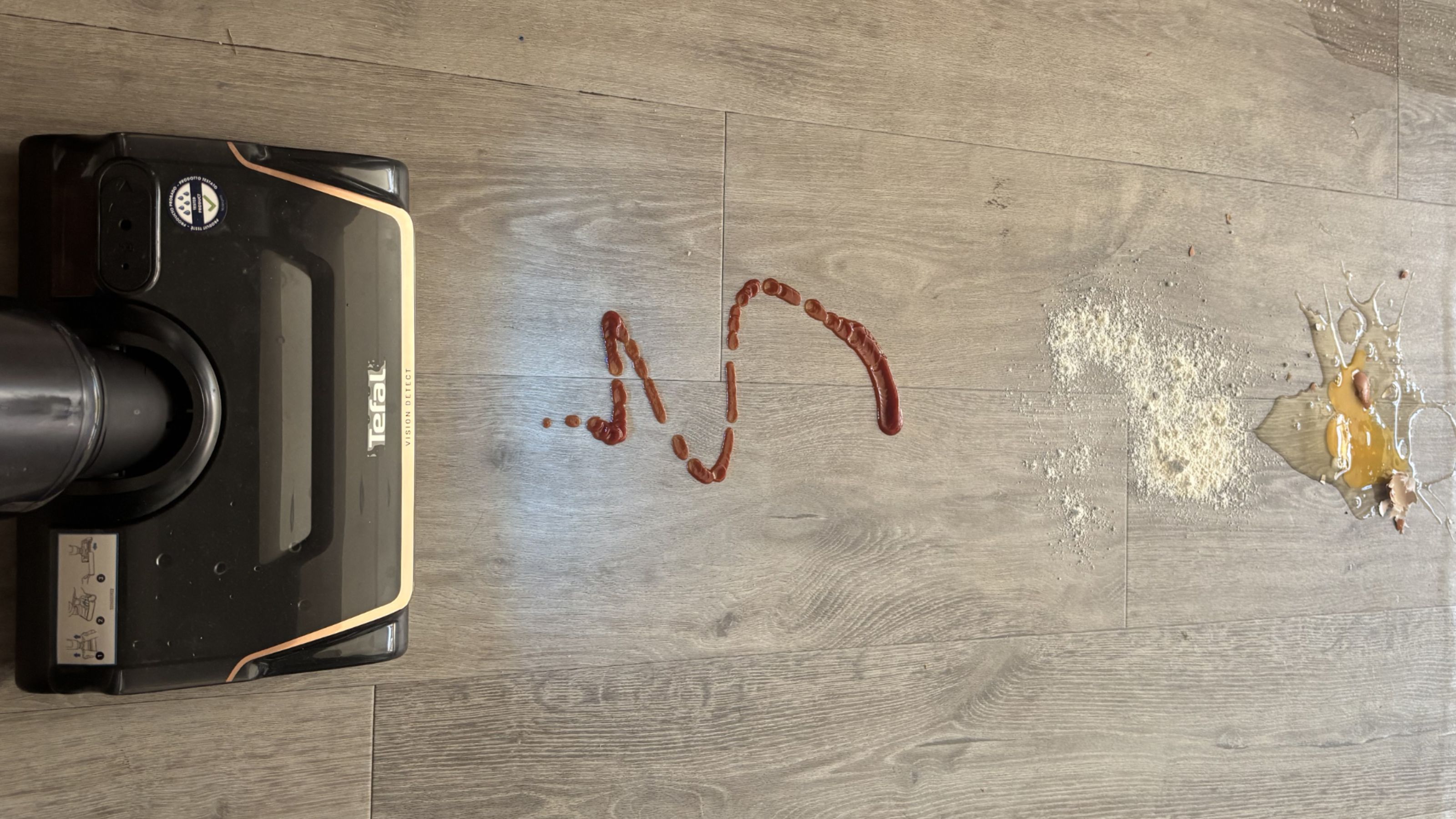 The Tefal X-Clean 7 vacuum mop cleaning up tomato sauce, flour and a cracked egg from grey hard flooring