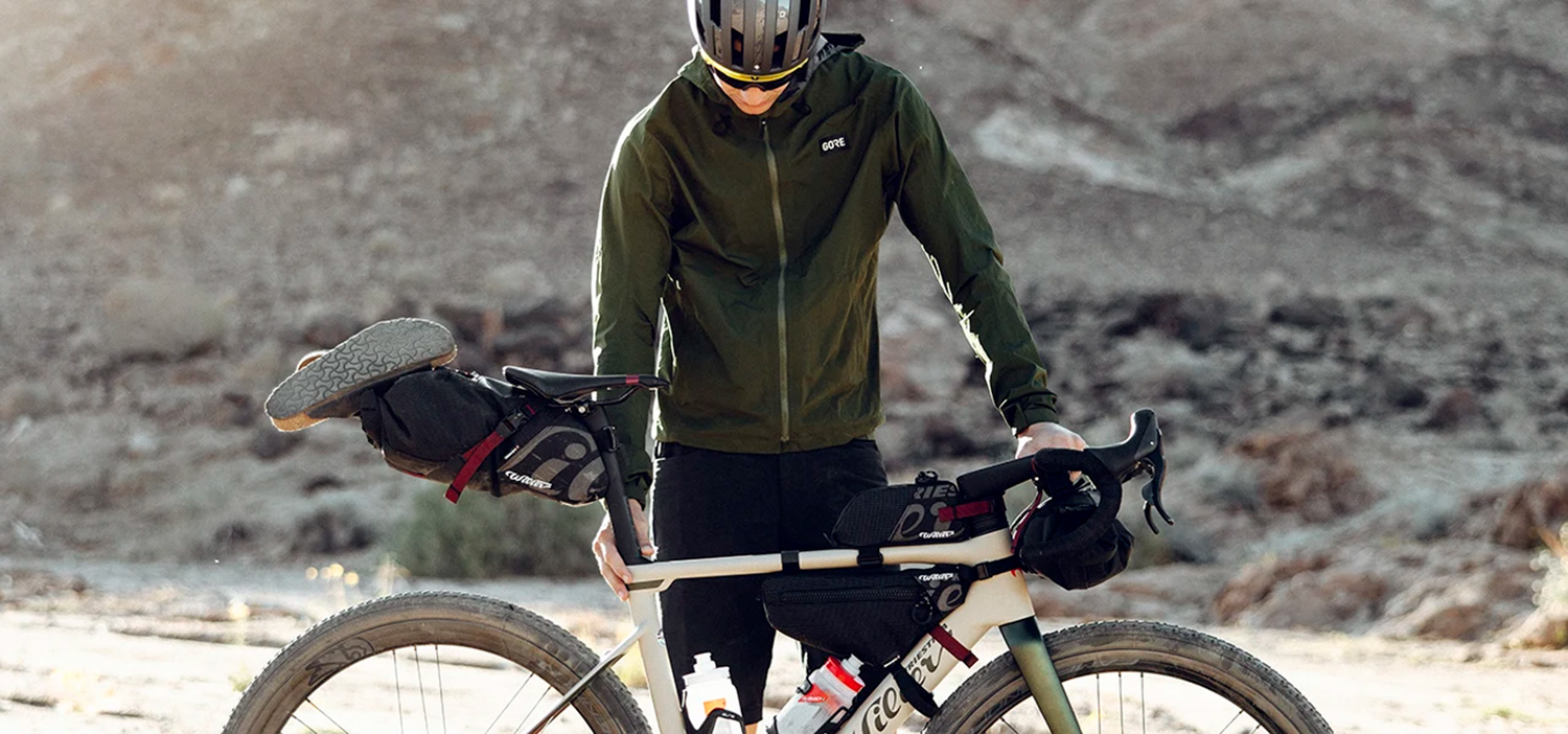 A man in a Gore-Tex jacket standing with his bike.