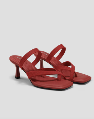 a pair of red strappy heels in front of a plain backdrop