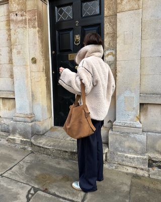 shearling jacket with a suede bag and tailored trousers