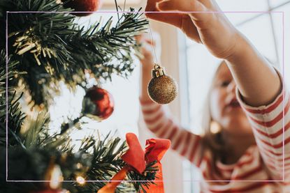 A child putting a bauble on a Christmas tree