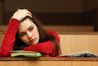 A young woman looks upset in a college classroom.