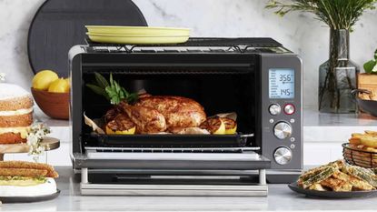 A Breville the Smart Oven with Air Fry Toaster Oven cooking a chicken, surrounded by other meals