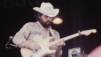 Lowell George playing a Fender Strat while wearing a cowboy hat