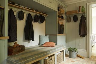 A mudroom with a tartan seat and plenty of hooks for hats and coats