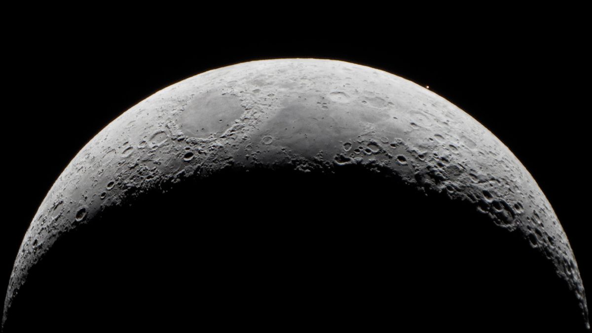 vista de cerca de la luna y hacia la parte superior derecha de la luna un pequeño punto de luz roja oxidada: Marte