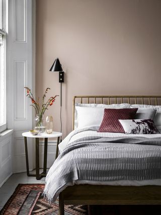 blush pink bedroom walls with colorful rug and a neutral bed. Bedroom idea by Perch and Parrow
