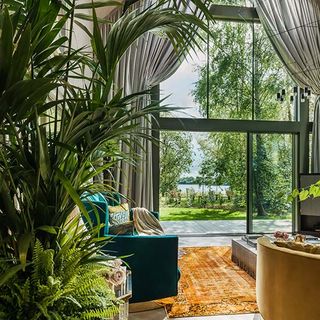 kate moss the Lakes by yoo living room with vast floor to ceiling windows and palm trees and tropical