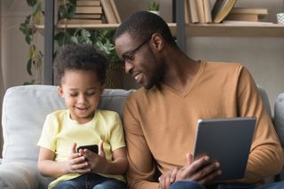 Father and daughter using mobile devices