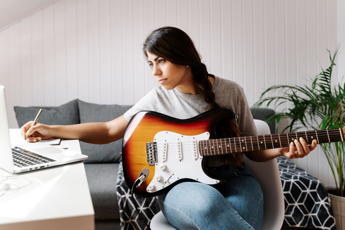 Woman takes notes while practicing guitar