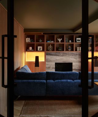 Low lit wood panelled living room with blue sofa