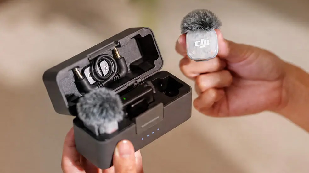 DJI Mic Mini 2S lifestyle image showing hand holding charging case and transmitter