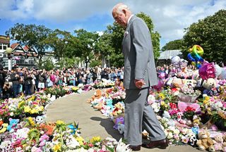 King Charles III views the tributes outside Southport Town Hall during his visit to members of the local community following the July 29 attack on a children's dance party on August 20, 2024 in Southport, England.