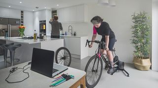 Woman riding connected turbo trainer in kitchen