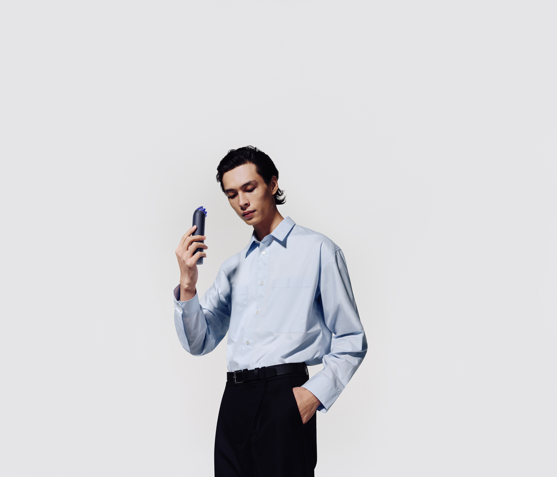an image of the mini hand held fan being used by a young man in a blue shirt and black trousers