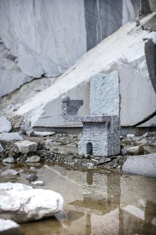 A stone chair by Max Lamb camouflaged on the rocks of a stone quarry in Northern Italy
