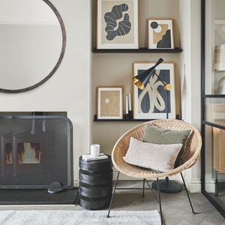 Living room with a fireplace, shelves in the alcove filled with picture frames, and a rattan bucket chair in front