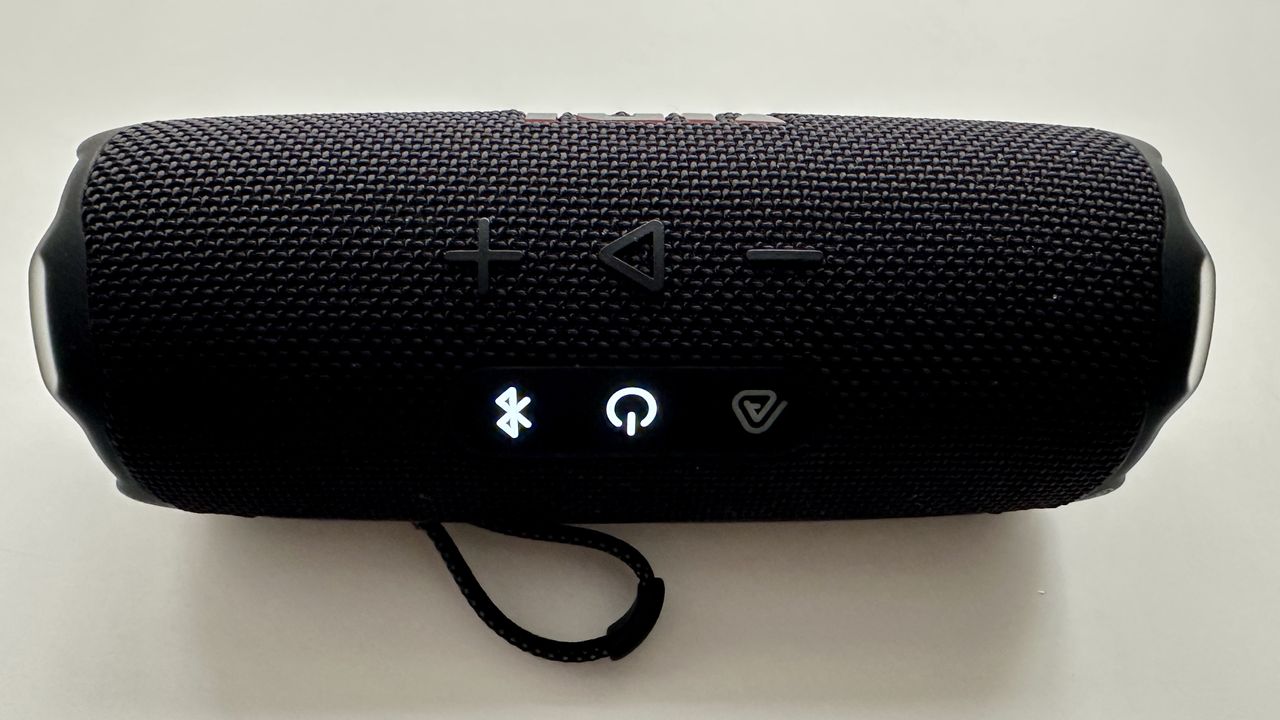 JBL Flip 7 portable Bluetooth speaker, with Power and Bluetooth lights on, on white surface