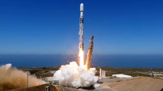 a rocket lifting off in front of a blue sky