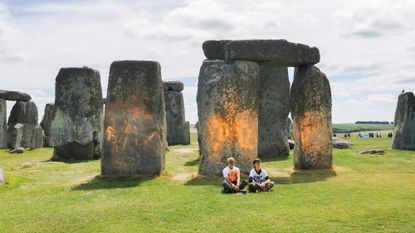 Protesters sit after spray painting the Stonehenge monument in England