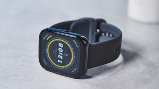 a black fitness tracker Amazfit Bip 5 showing the default yellow and blue toned watch face and fitness capabilities