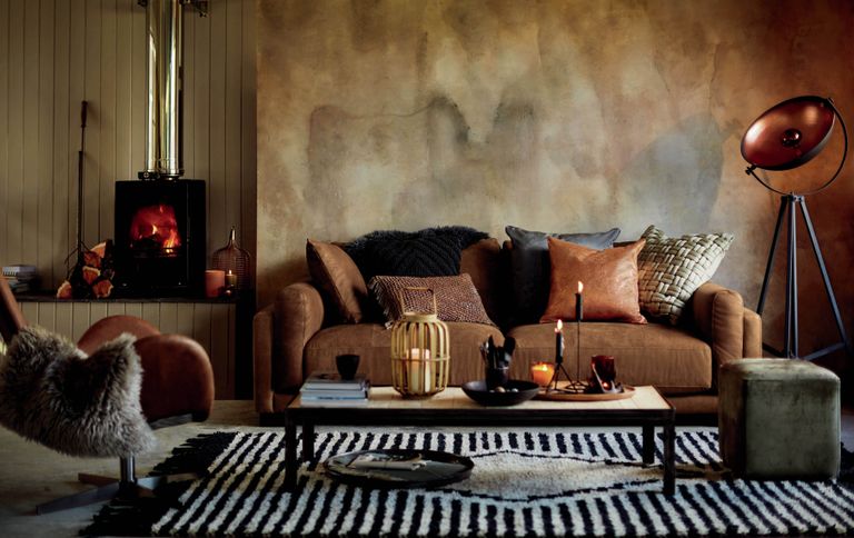 Balboa brown three seater leather sofa with various textured cushions, striped rug, wood burner and plaster effect walls