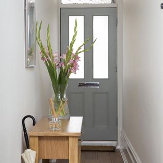 room with white wall door and flower pot on wooden stool