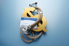 A stethoscope is wrapped arounf a gold dollar symbol and a Medicare card.