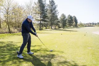 A golfer swinging slowly off the tee