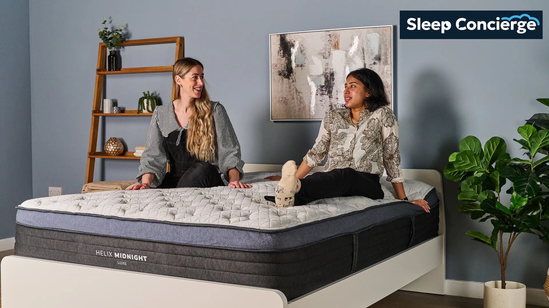 Tom's Guide Sleep Concierge team image shows two of our mattress testers sitting on a luxury hybrid mattress in our sleep product testing lab