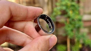 The Ultrahuman Ring Air held in fingertips to show the Ultrahuman logo engraved inside.