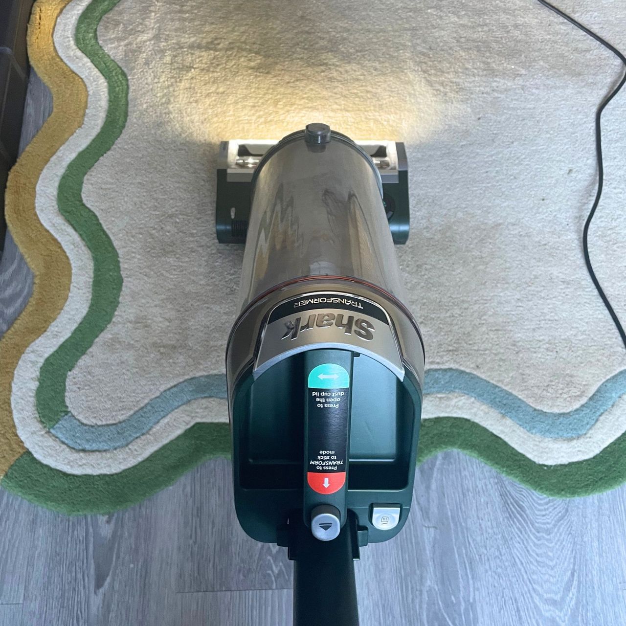Shark PowerDetect Transformer Corded Upright Vacuum Cleaner cleaning a cream rug with colourful wiggle pattern around the outside