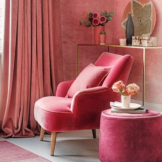 Hot pink and deep berry velvet sofa and pouffes next to curtain