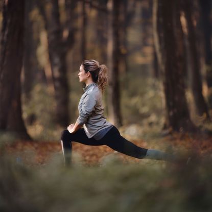 Working out in winter: A woman stretching in an autumnal-looking forest