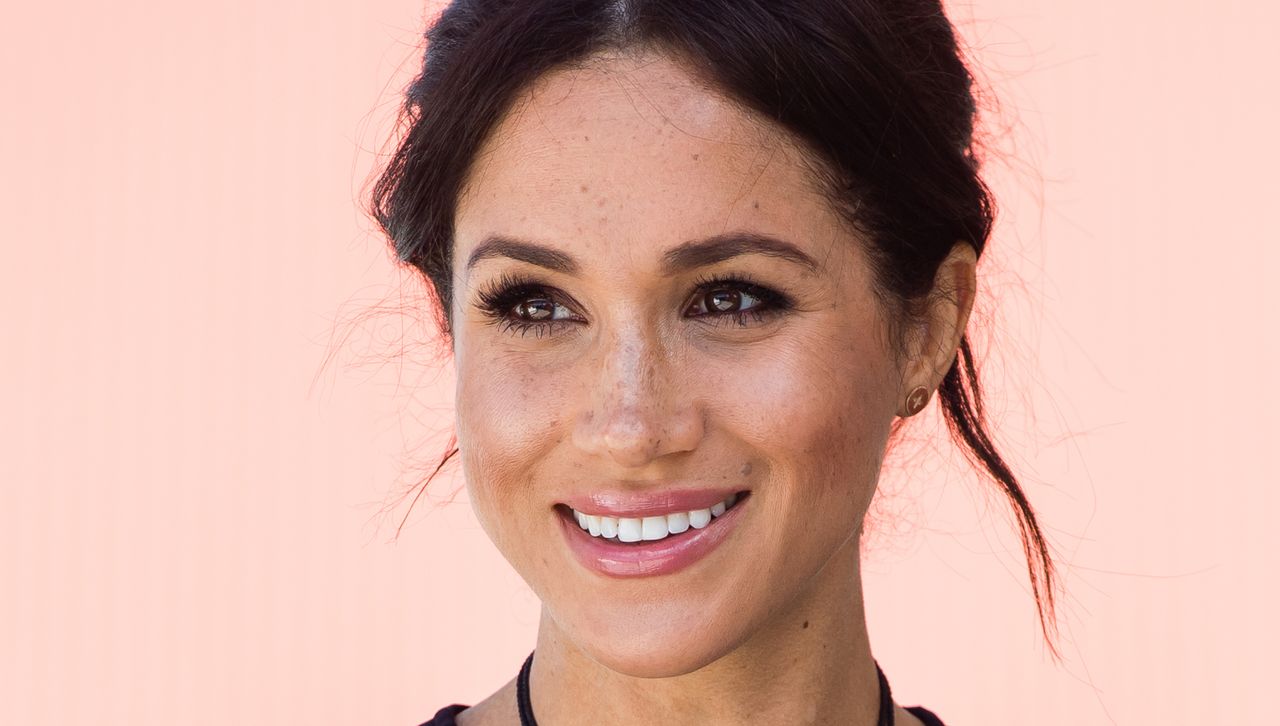 A close up of Meghan Markle wearing a black dress and eye makeup