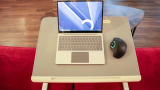 A trackball mouse next to a laptop on a lap desk