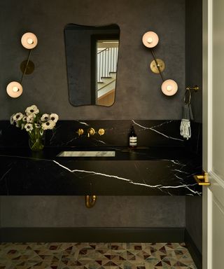 Charcoal gray textured walls, marble vanity, pendant lights brass fixtures and fittings, small scale floor tiles