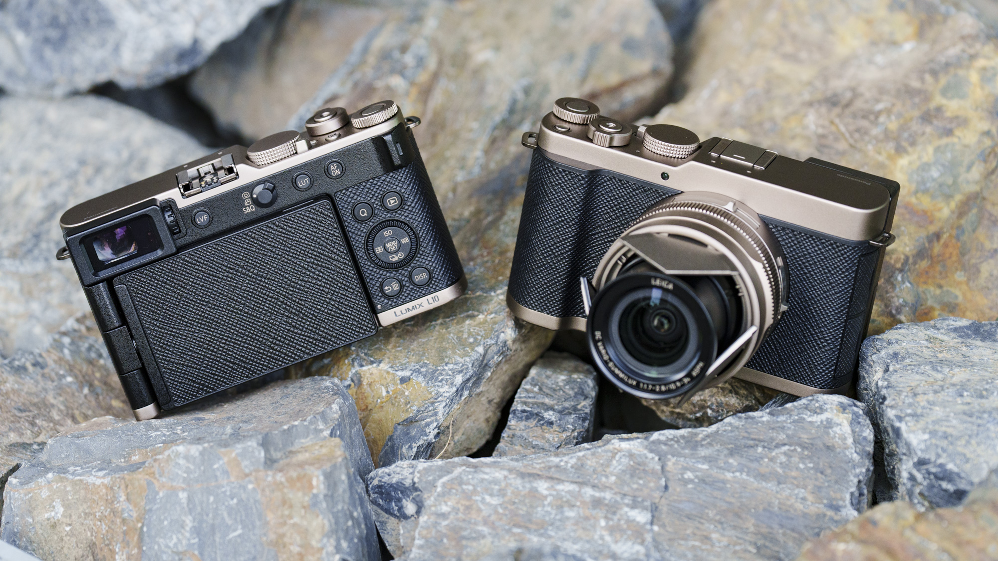 The Gold Titanium Special Edition of the Panasonic Lumix L10 compact camera, sat on gray and rust-colored rocks