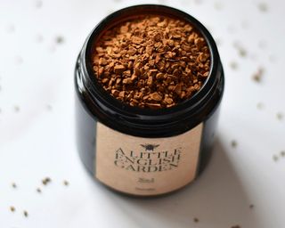 An amber colored candle jar filled with freeze-dried instant coffee
