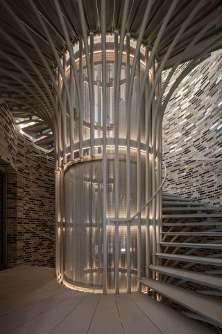 Fjordenhus, by Olafur Eliasson and Studio Olafur Eliasson in Vejle, Denmark. A face brick staircase spiraling around a rounded elevator shaft.